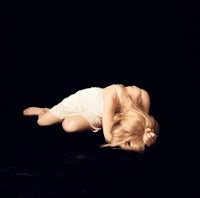 a woman in a white dress laying on a black background